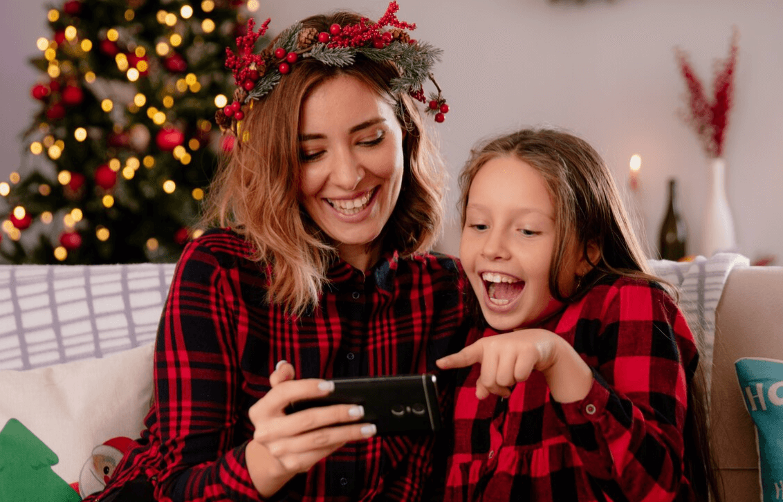 A mum and her daughter laughing at a personalised video from Santa on a phone