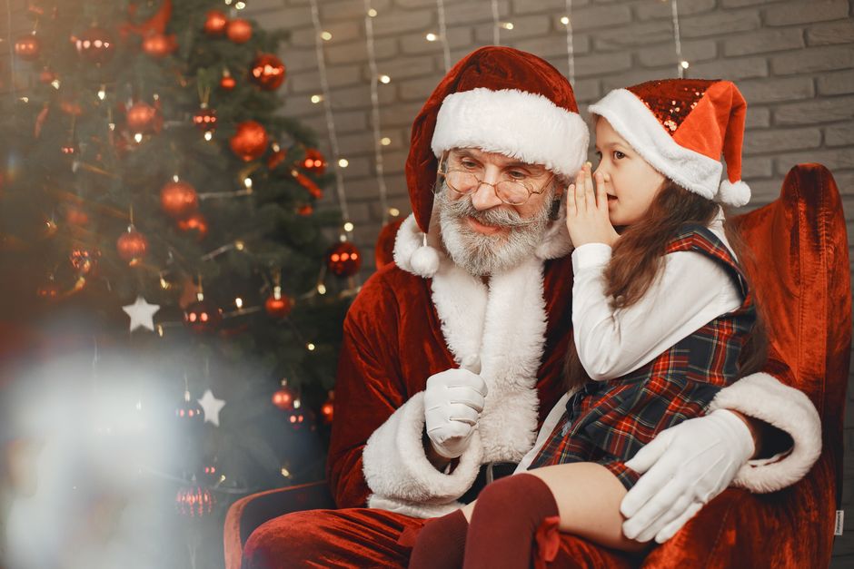 Santa Claus listening to a little girl whisper her Christmas wish